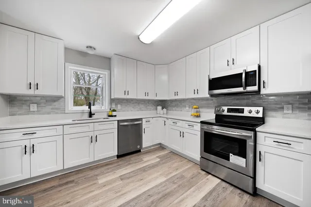 a kitchen with granite countertop a stove a sink and a microwave