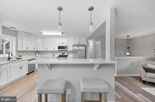 a kitchen with stainless steel appliances granite countertop a sink a stove and chairs