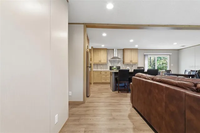 a living room with stainless steel appliances kitchen island granite countertop a refrigerator and a sink