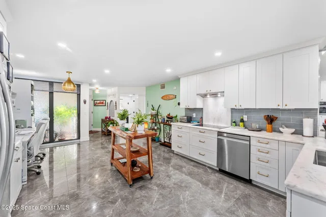 a living room with stainless steel appliances furniture a rug and a kitchen view