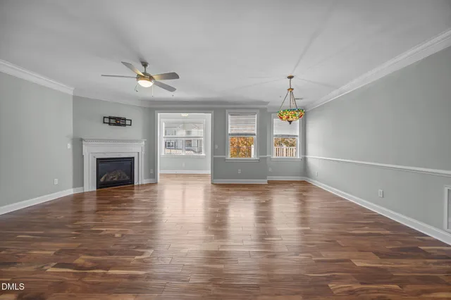 a view of an empty room with window and wooden floor