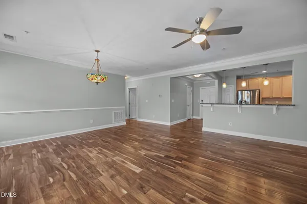 a view of an empty room with a window and a kitchen