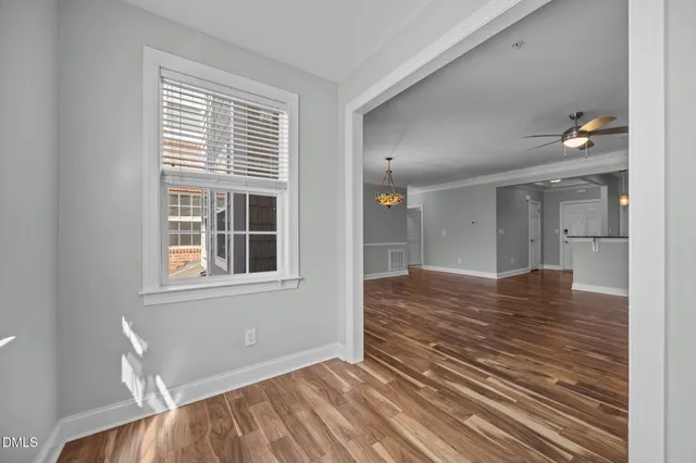 a view of empty room with wooden floor and fan