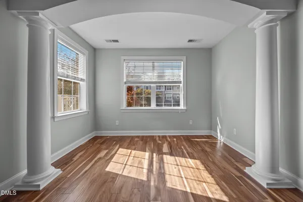 a view of an empty room with wooden floor and a window