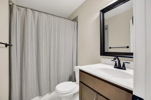 a bathroom with a sink a toilet a mirror and shower curtain