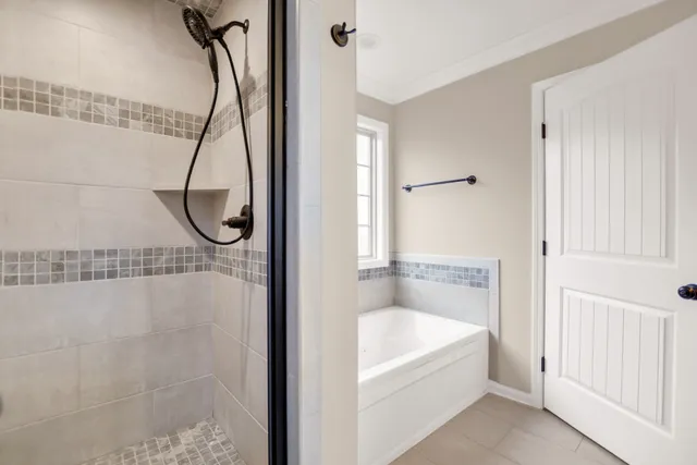 a bathroom with a bath tub a mirror and a shower