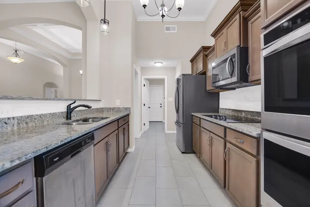 a kitchen with stainless steel appliances granite countertop a sink and a stove top oven with wooden floor