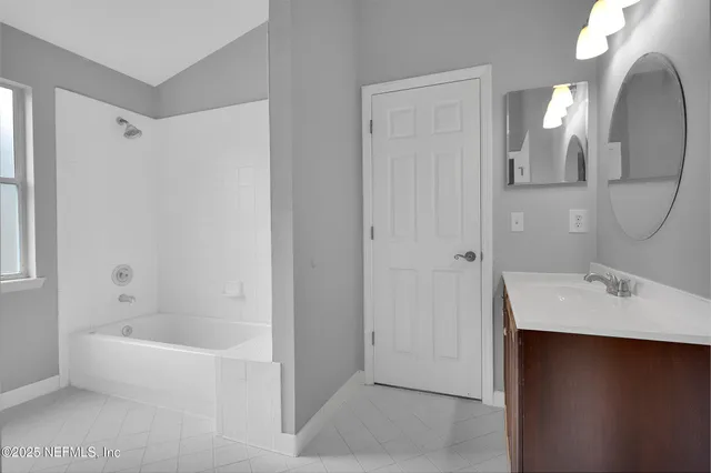 an empty room with a chandelier fan and windows