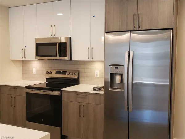 a kitchen with stainless steel appliances granite countertop a refrigerator a stove and a sink with wooden floor