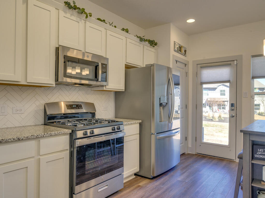 2257 Local Rebel Loop Leander, TX 78641 - Photo 12 of 26 a kitchen with stainless steel appliances white cabinets and a stove top oven