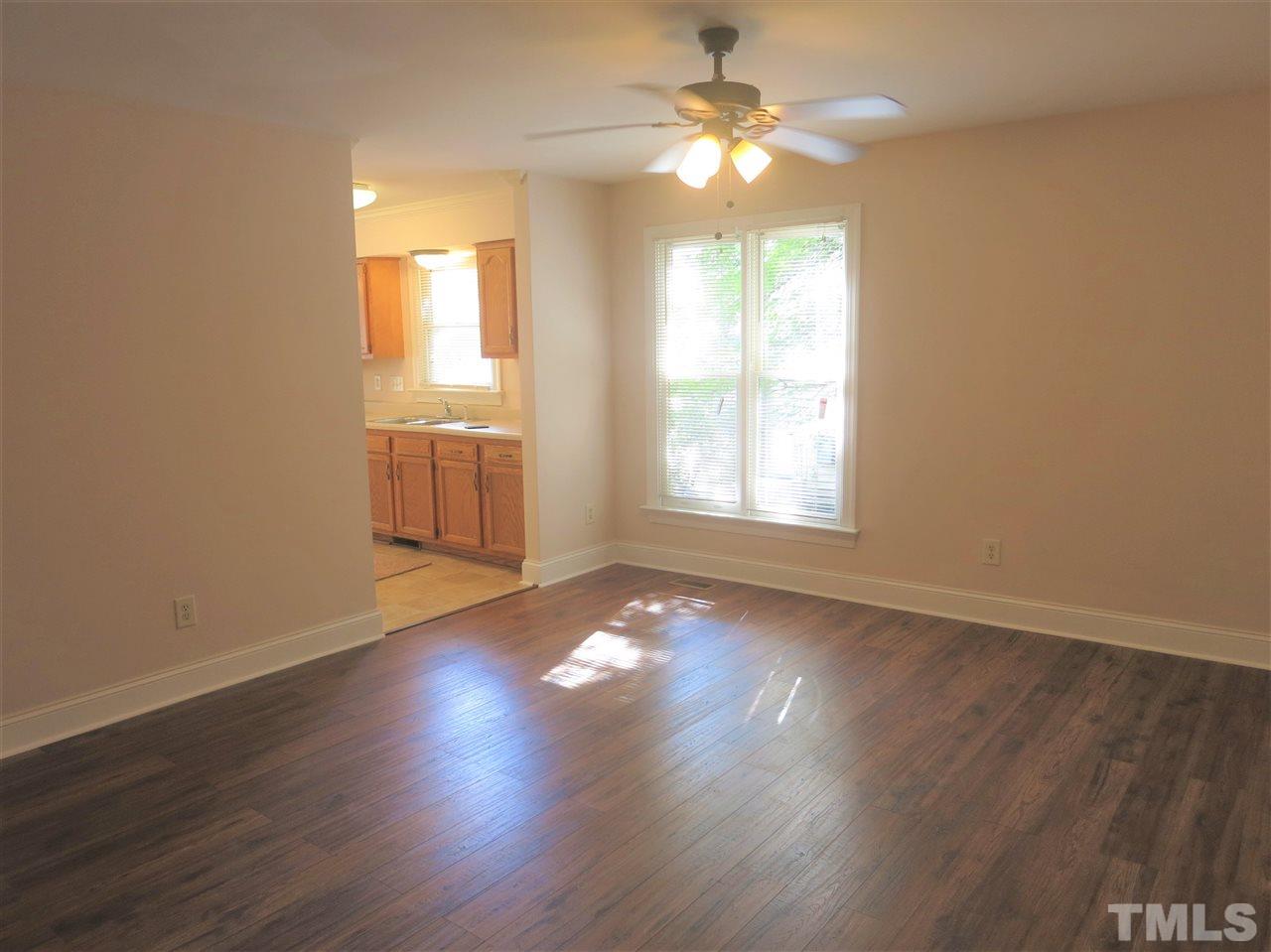 509 Brent Road Raleigh, NC 27606 - Photo 4 of 9 an empty room with wooden floor chandelier fan and windows