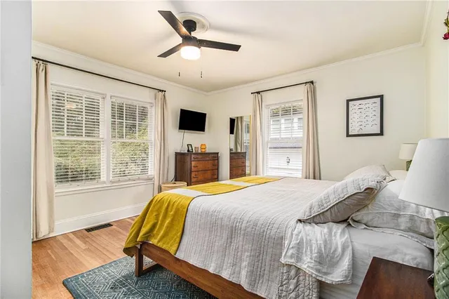 a bedroom with a bed painting on wall and a large window