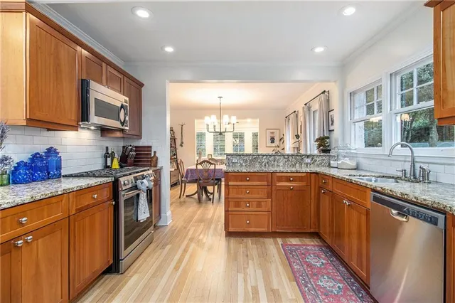 a large kitchen with stainless steel appliances granite countertop a stove a sink dishwasher and a microwave oven with wooden cabinets