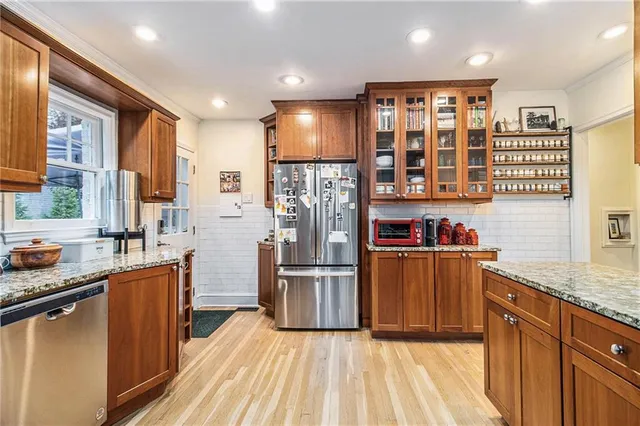 a kitchen with stainless steel appliances granite countertop a refrigerator oven a sink dishwasher and wooden cabinets with wooden floor