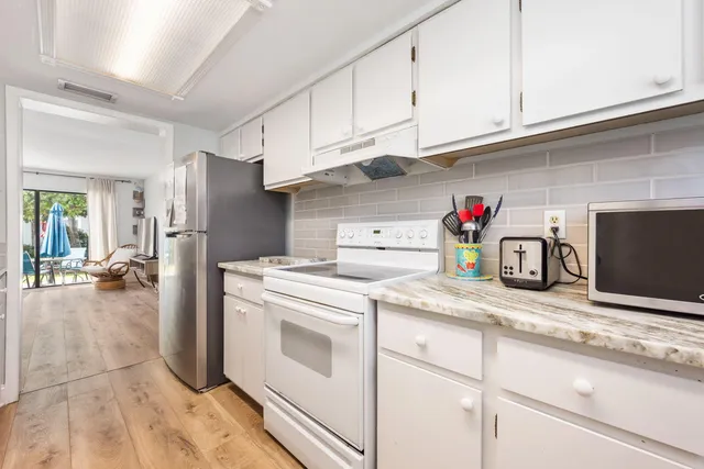 a kitchen with granite countertop a sink dishwasher a stove and a refrigerator with cabinets