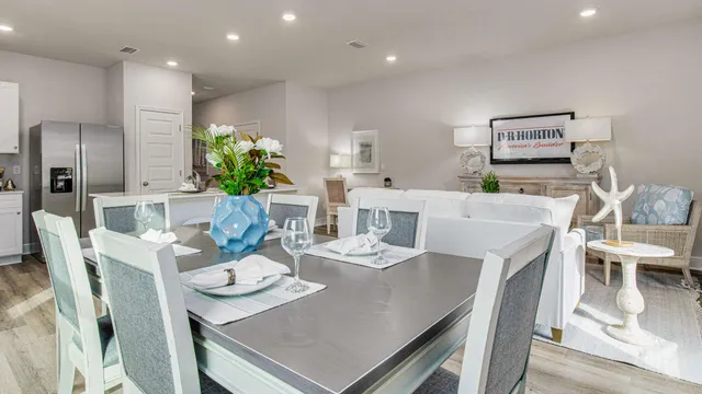 a living room with stainless steel appliances furniture dining table and wooden floor