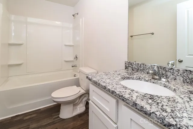 a bathroom with a granite countertop toilet a sink and a bathtub