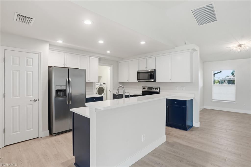 1808 Southwest 30th Street Cape Coral, FL 33914 - Photo 11 of 44 a kitchen with stainless steel appliances granite countertop a refrigerator a stove top oven a sink and dishwasher with wooden floor