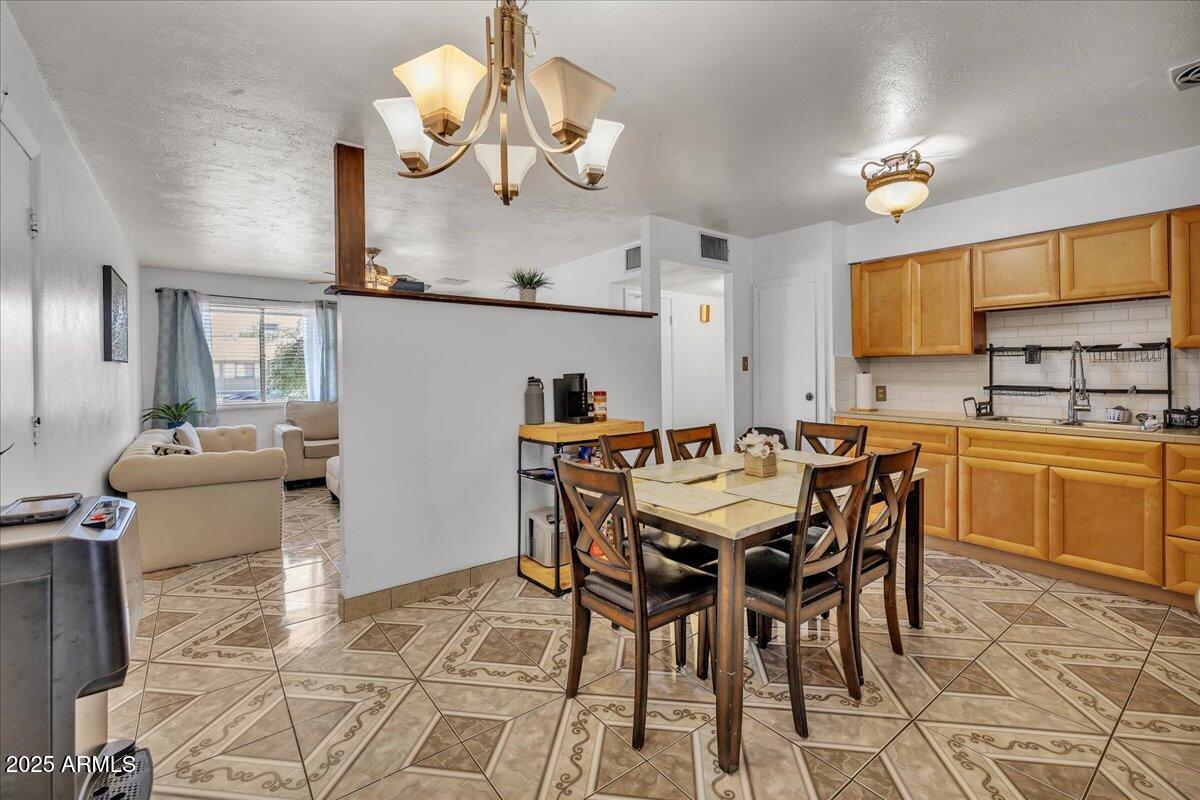 a dining room filled chandelier and kitchen view