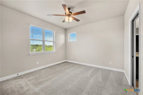 an empty room with ceiling fan and windows