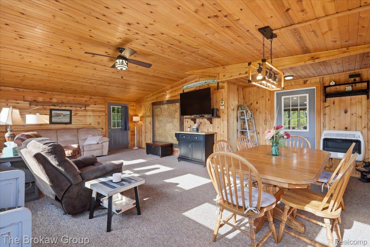 5461 North Henderson Road Davison, MI 48423 - Photo 26 of 64 Wood-paneled interior featuring a dining area with a wooden table and matching chairs, a ceiling fan, and a light-colored carpeted floor