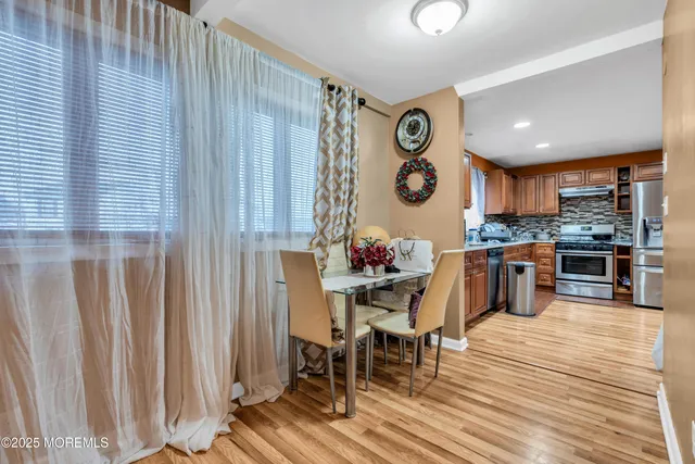 a kitchen with stainless steel appliances granite countertop a dining table chairs and a refrigerator