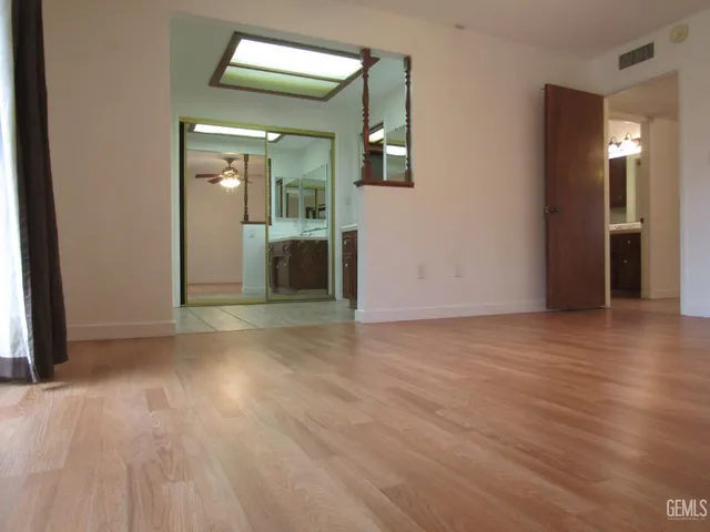 an empty room with wooden floor and mirror