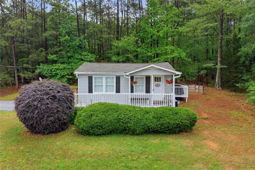 Charming cottage with a welcoming front porch nestled in a serene, wooded setting.
