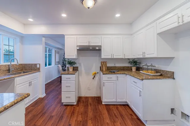 a kitchen with granite countertop wooden floors and white stainless steel appliances