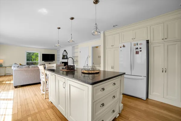 a kitchen with stainless steel appliances granite countertop a refrigerator a sink dishwasher a oven and a dining table with wooden floor