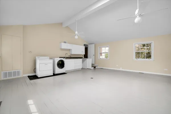 a view of a livingroom with a fridge a ceiling fan and wooden floor