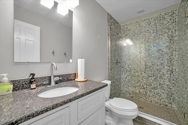 a bathroom with a granite countertop sink toilet and a mirror