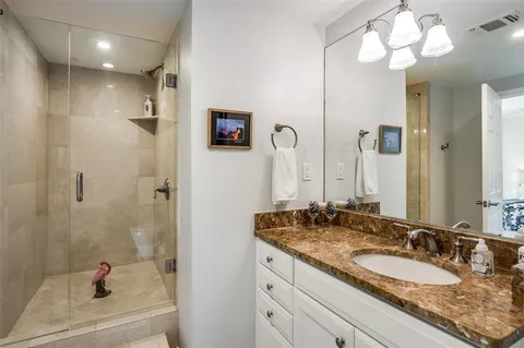 a bathroom with a granite countertop sink a mirror and shower