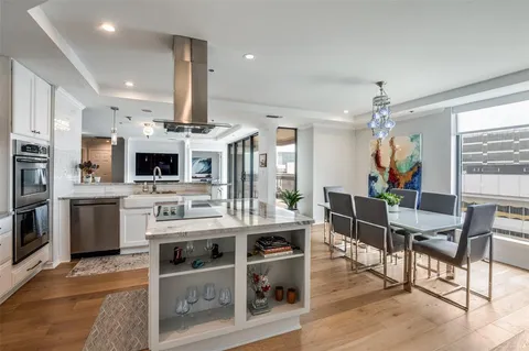 a living room with stainless steel appliances kitchen island granite countertop a table chairs and a stove