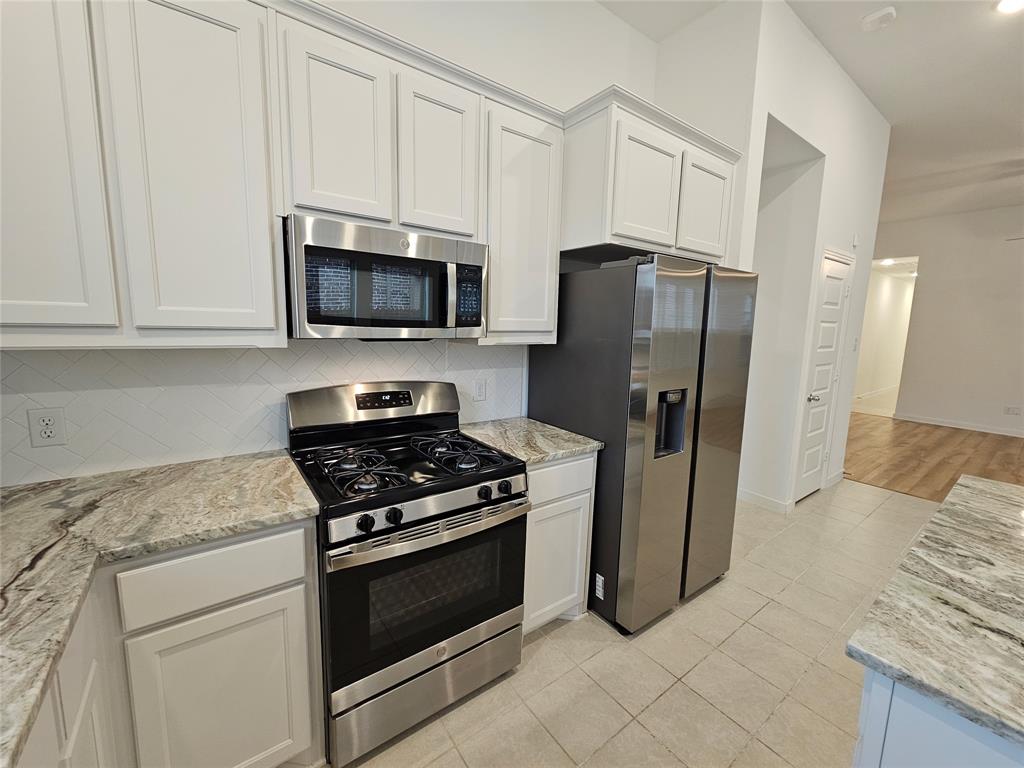 3915 Chesapeake Lane Crandall, TX 75114 - Photo 2 of 32 a kitchen with stainless steel appliances granite countertop a refrigerator stove and microwave
