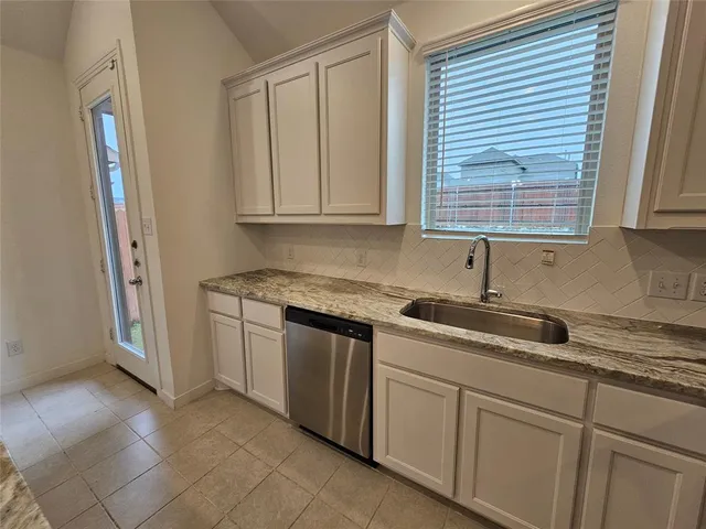 a kitchen with granite countertop a sink and a white cabinets