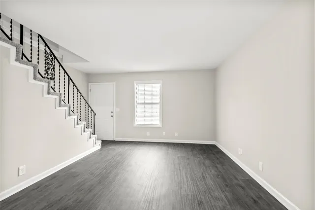 a view of an empty room with wooden floor and stairs