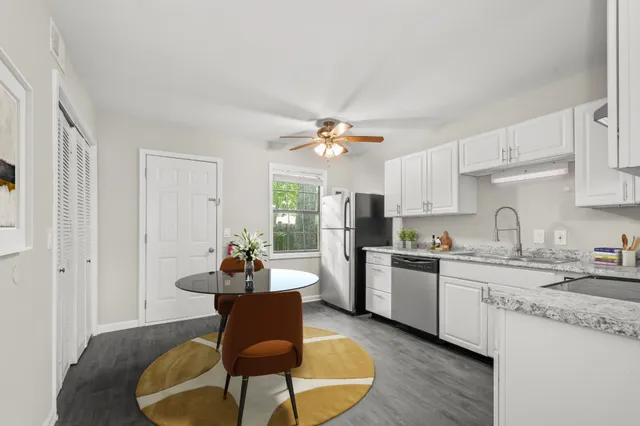 a kitchen with a dining table chairs and white cabinets