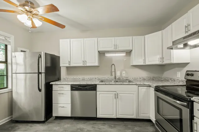 a kitchen with white cabinets white stainless steel appliances and sink