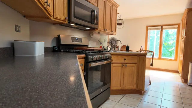 a kitchen with stainless steel appliances granite countertop a stove a sink and a microwave