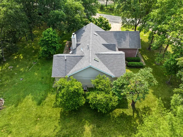 an aerial view of a house with a yard and a large tree