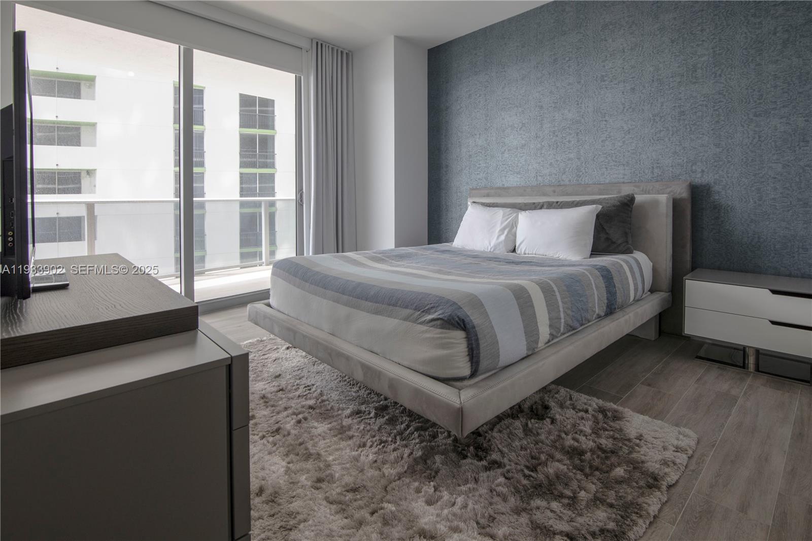 488 Northeast 18th Street, Unit 2610 Miami, FL 33132 - Photo 16 of 21 a spacious bedroom with a bed and wooden floor