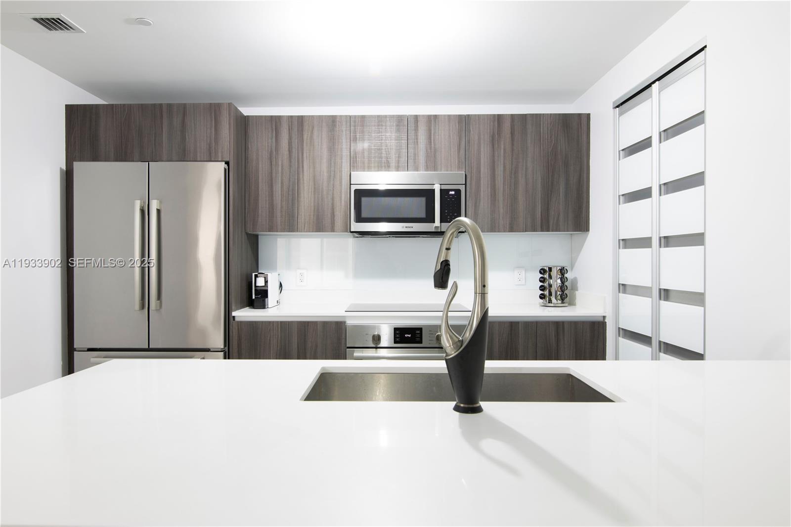 488 Northeast 18th Street, Unit 2610 Miami, FL 33132 - Photo 8 of 21 a kitchen with granite countertop a refrigerator and a stove top oven