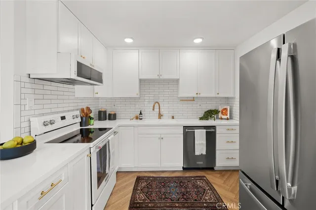 a kitchen with stainless steel appliances a stove a sink and white cabinets