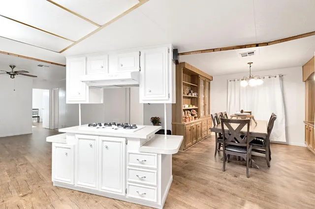 a dining hall with stainless steel appliances kitchen island granite countertop a table chairs and a refrigerator