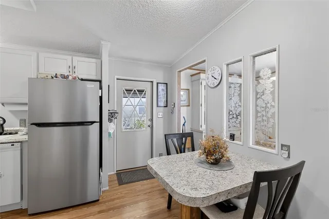 a kitchen with refrigerator and wooden floor
