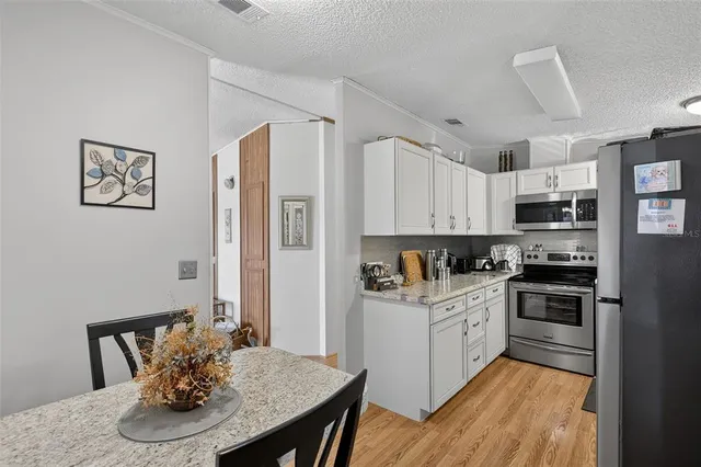 a kitchen with stainless steel appliances kitchen island granite countertop a refrigerator a stove a sink dishwasher with a dining table and chairs