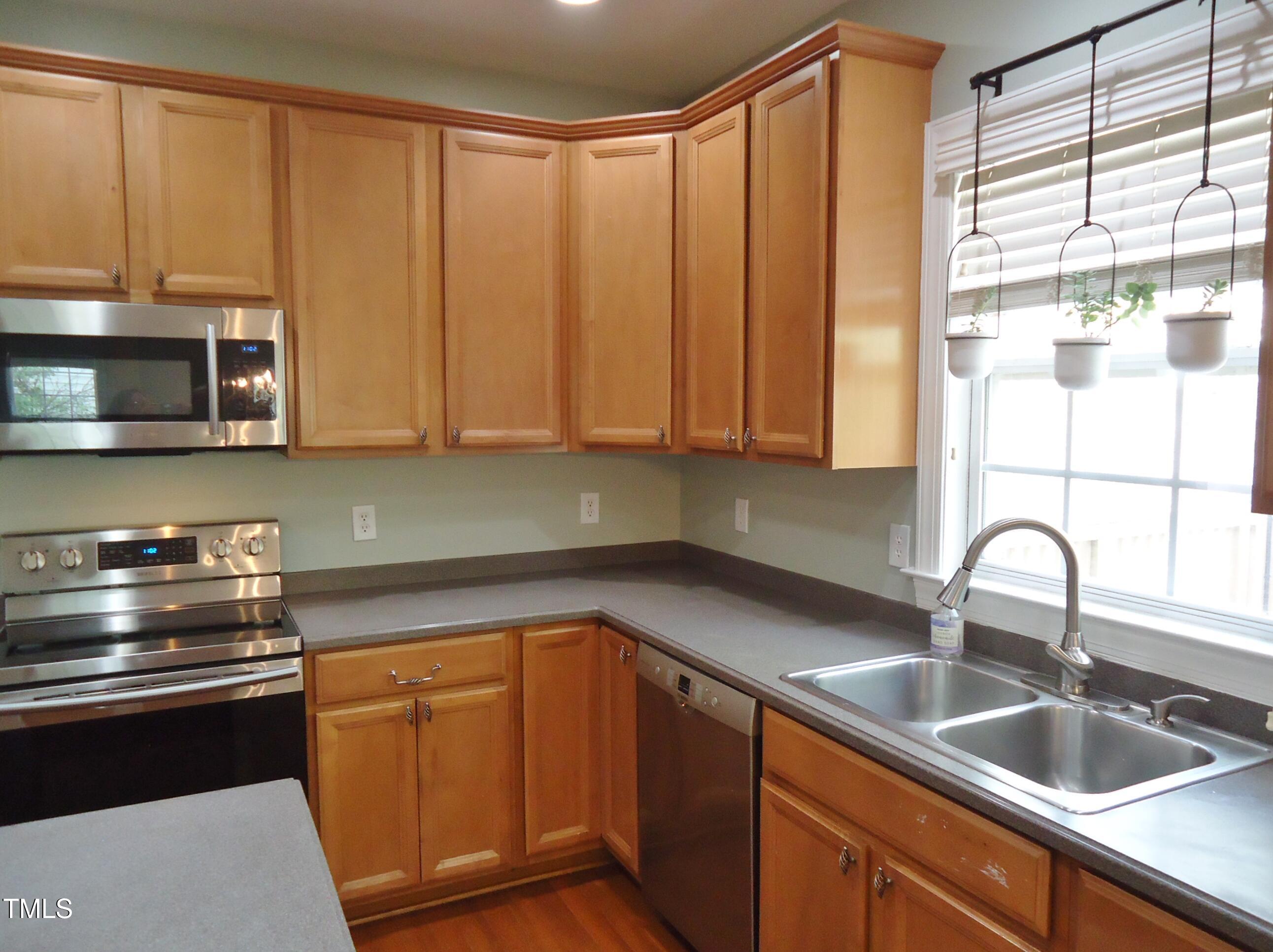 109 Bright Shade Court Holly Springs, NC 27540 - Photo 13 of 46 a kitchen with stainless steel appliances granite countertop a sink a microwave cabinets and a window