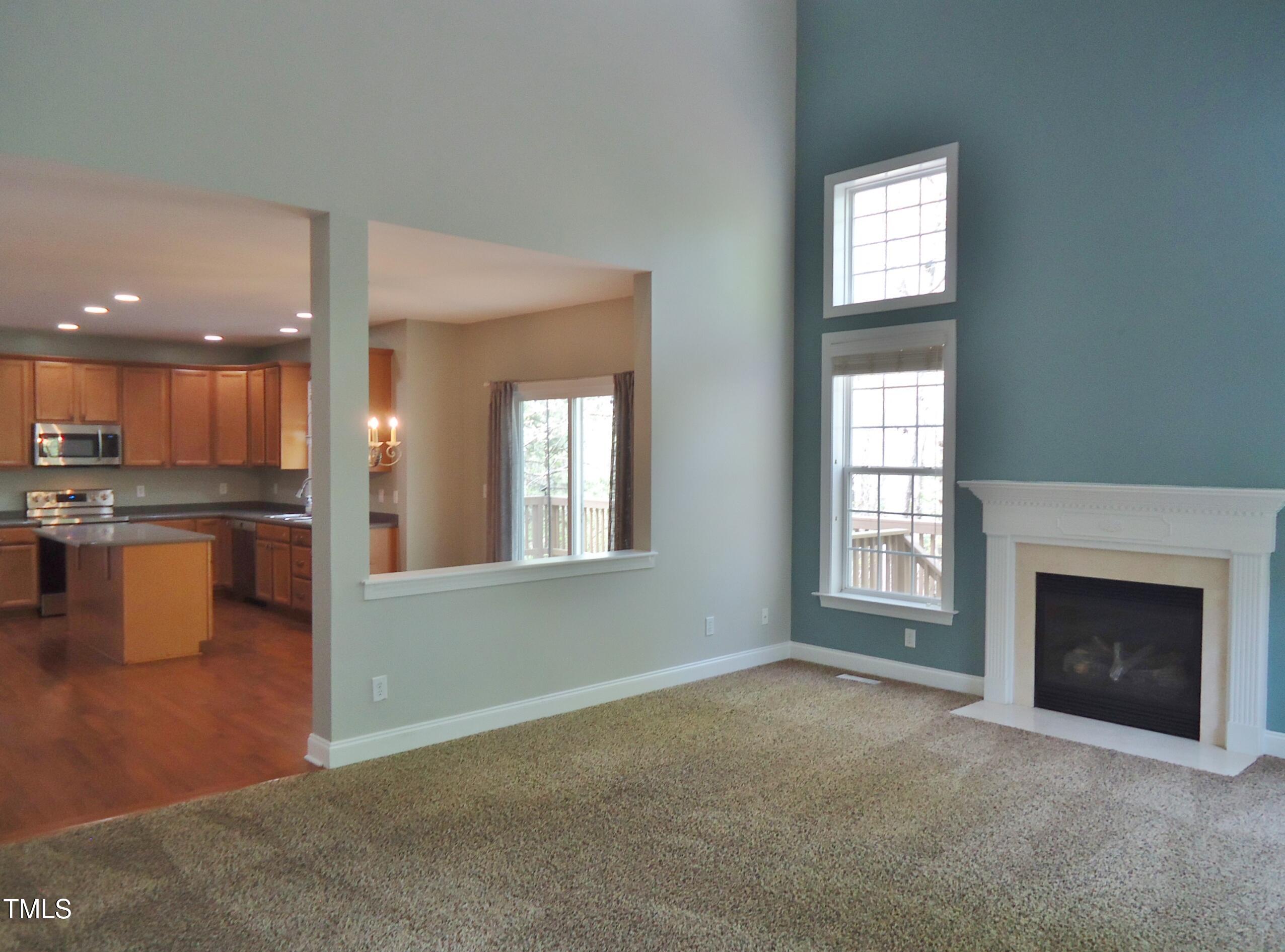 109 Bright Shade Court Holly Springs, NC 27540 - Photo 24 of 46 an empty room with kitchen view and a fireplace