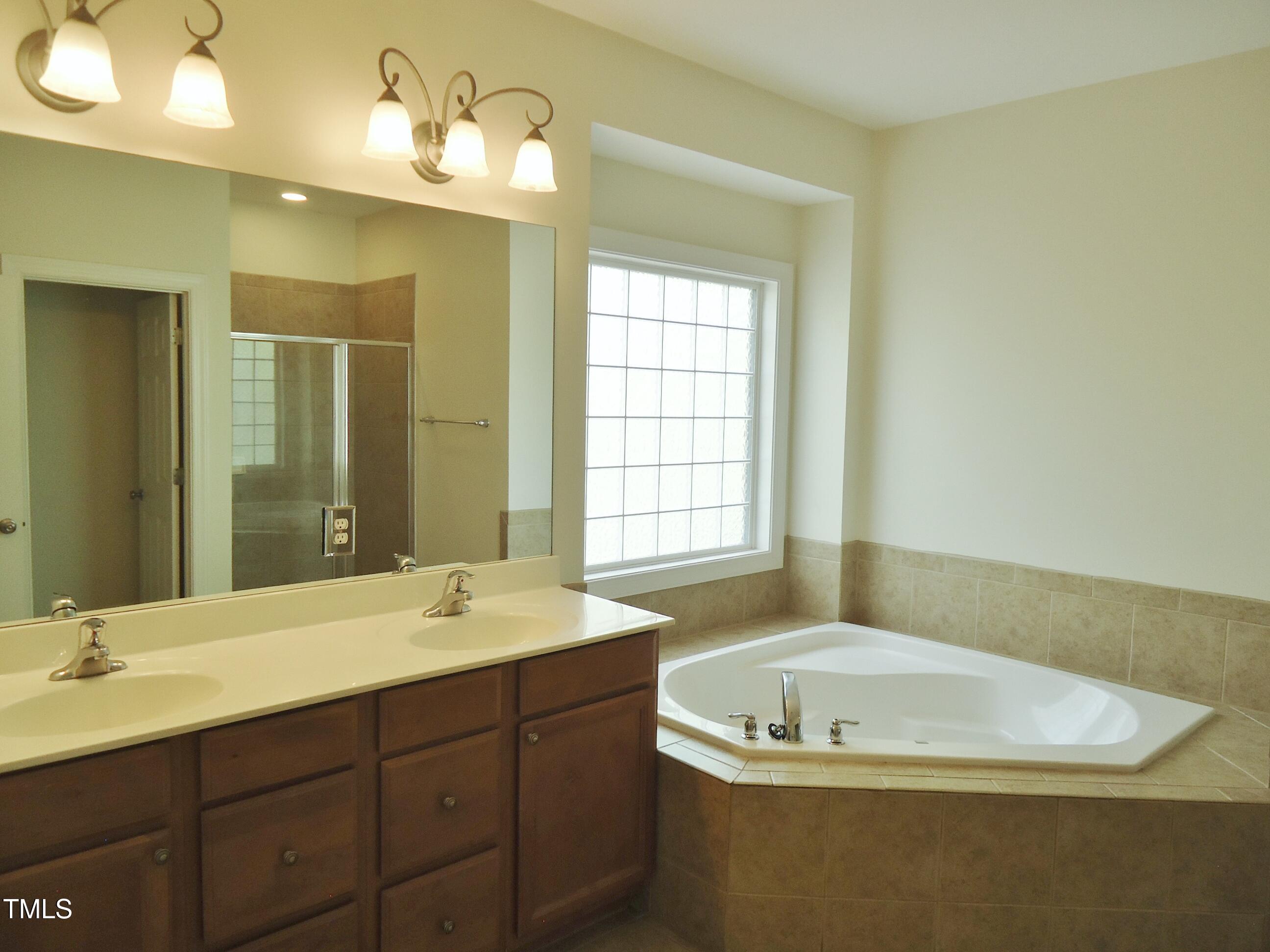 109 Bright Shade Court Holly Springs, NC 27540 - Photo 32 of 46 a bathroom with a tub a sink double vanity and a mirror